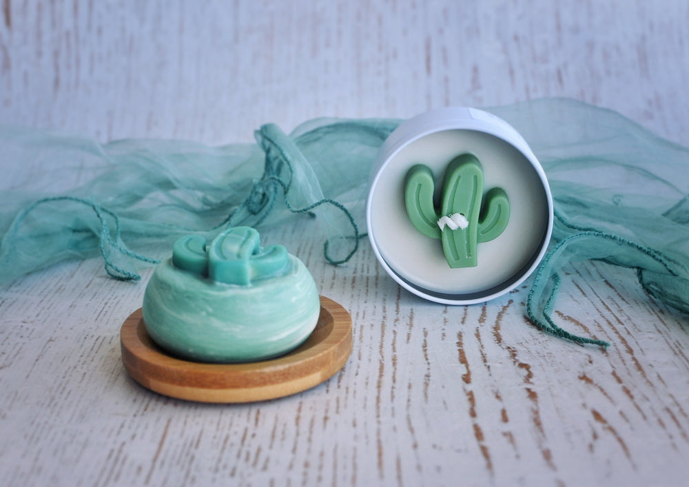 white tin cactus candle and a round green cactus soap on a bamboo soap dish styled with a similar colour scarf