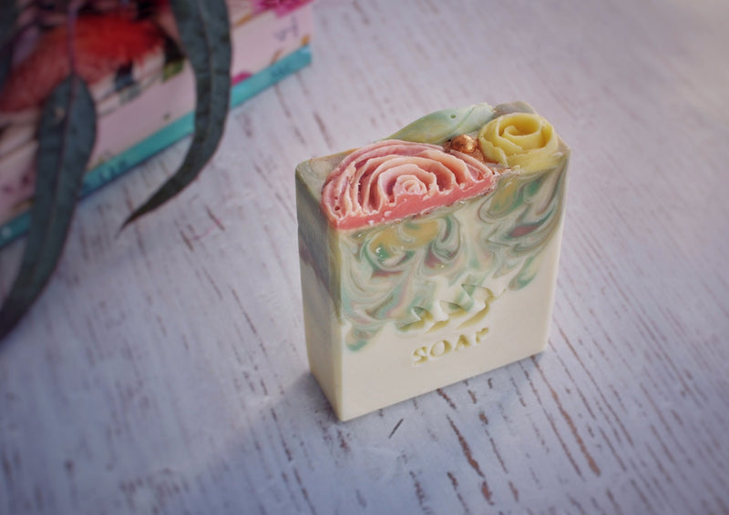 white base soap with drop swirl in green, yellow, orange with soap flower decoration 