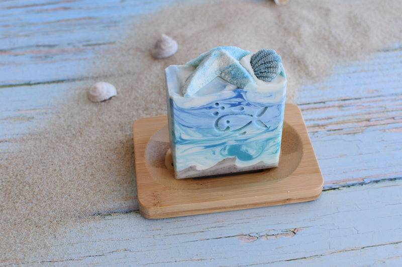 Sea themed soap in blue and sand colour with sea star and sea urchin decoration on top on a bamboo soap dish 